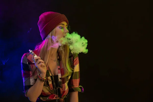 Rapariga vacilante. Mulher jovem hipster vape e-cig em fundo preto. Estilo hip-hop. Estúdio — Fotografia de Stock