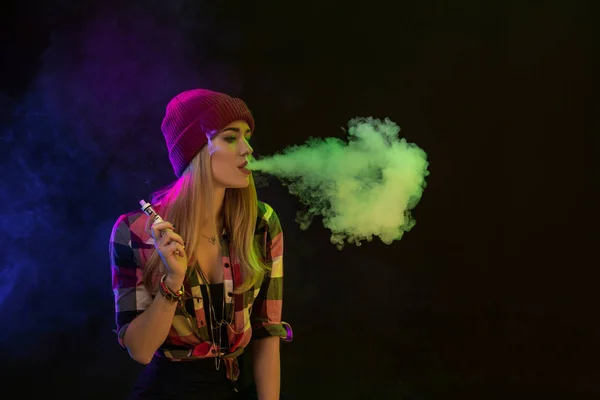 Vaping 女孩年轻的时髦女人 vape 在黑色背景上的电子香烟。嘻哈风格。工作室拍摄 — 图库照片