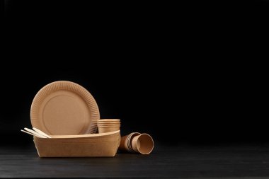 Çevre dostu tek kullanımlık sofra takımı siyah arka planda duruyor. Biyo-çözünebilir el yapımı yemekler. Geri dönüşüm konsepti. Yakın çekim..