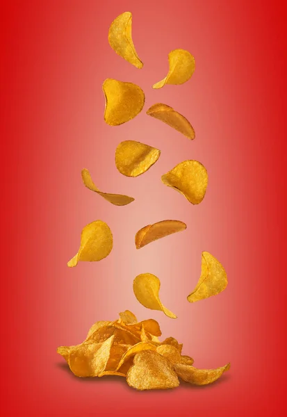 Картофельные чипсы, падающие на красном фоне с пространством для копирования текста или изображений. Хрустящие, вкусные чипсы. Реклама. Закрытие. — стоковое фото