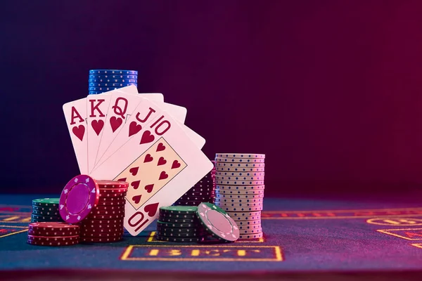 Winning combination in poker standing leaning on multicolored chips piles on blue cover of playing table. Black background. Casino concept. Close-up. — Stock Photo, Image