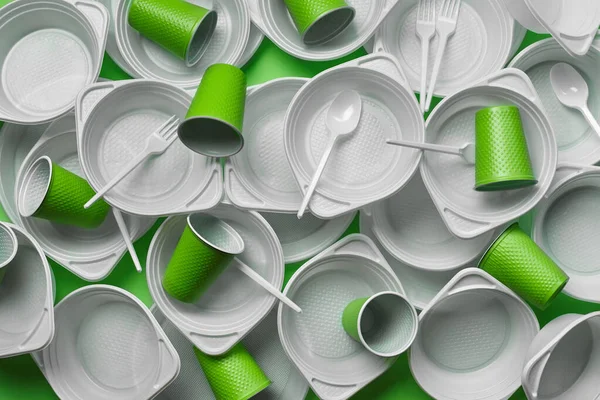 White plastic disposable tableware on green background with copy space. The concept of picnic utensil. Top view. Selective focus. Close-up. — Stock Photo, Image