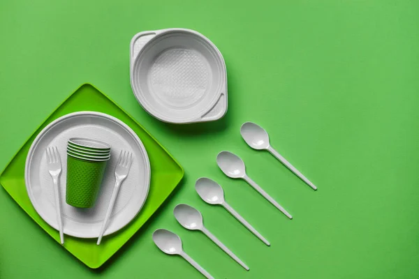 Kleurrijk plastic wegwerp servies op groene achtergrond met kopieerruimte. Het concept van picknickgereedschap. Bovenaanzicht. Selectieve focus. Close-up. — Stockfoto