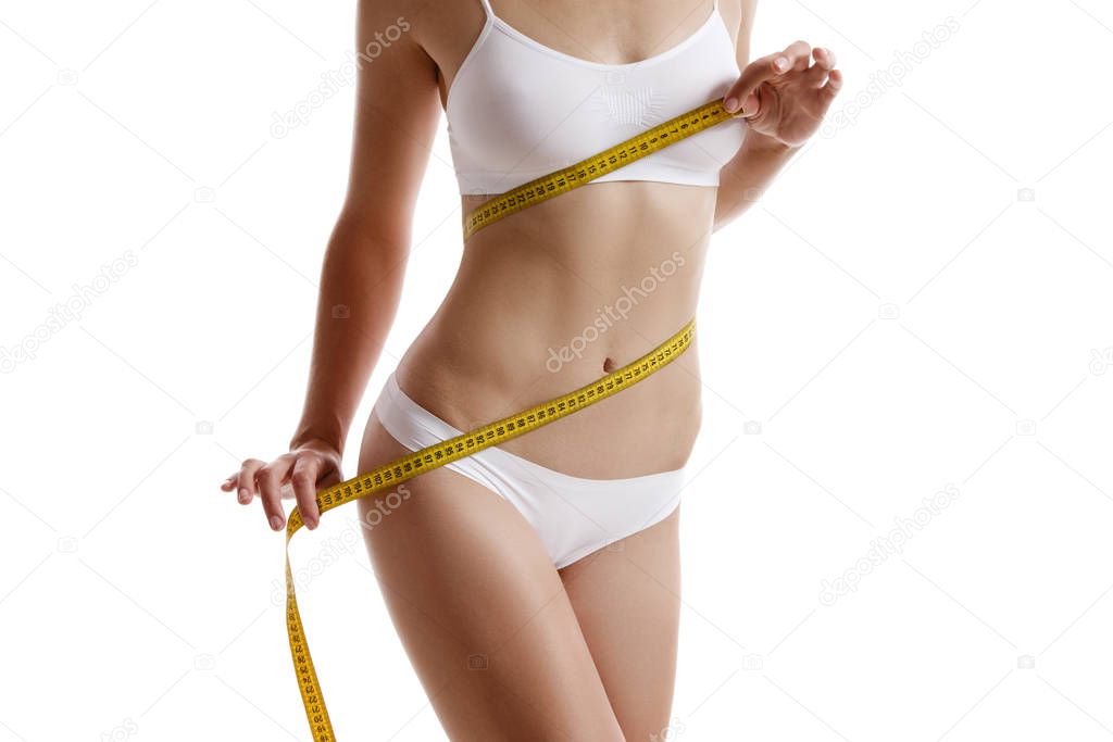Perfect body of girl in white underwear measuring herself, posing isolated on white. Plastic surgery and aesthetic cosmetology concept. Close-up.
