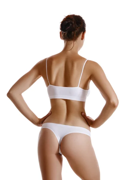 Perfecto, delgado, cuerpo joven de una niña con ropa interior blanca que representa la espalda, aislado en blanco. Cirugía plástica y concepto de cosmetología estética. Cierre. — Foto de Stock