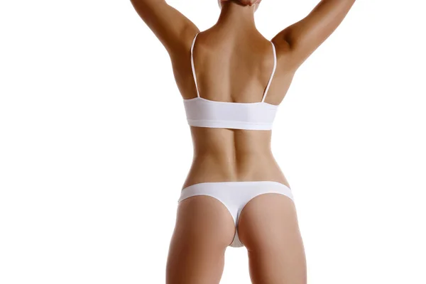 Dokonalé, štíhlé, mladé tělo dívky v bílém spodním prádle pózující vzadu, izolované na bílém. Plastická chirurgie a estetická kosmetologie. Detailní záběr. — Stock fotografie