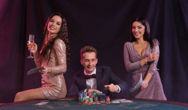 Kumarhanede poker oynayan bir adam masada çip yığınlarıyla oturuyor.