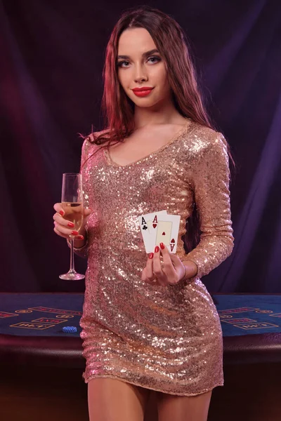 Woman in golden dress showing cards, holding champagne while pos — Stock Photo, Image