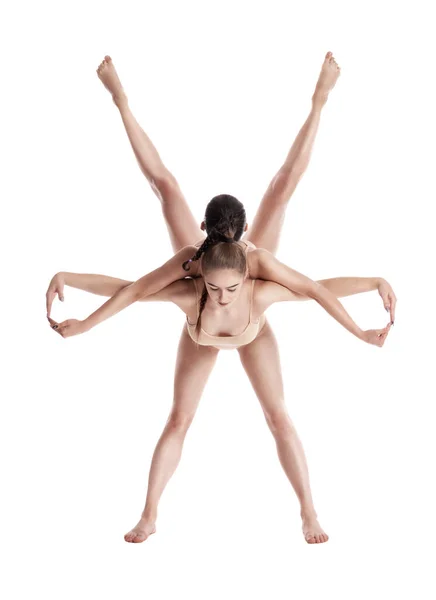 Dvě flexibilní dívky gymnastky v béžových trikotech provádějí cvičení pomocí podpory a pózování izolované na bílém pozadí. Detailní záběr. — Stock fotografie