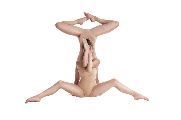 Duas meninas flexíveis ginastas em leotards bege realizando elementos complexos de ginástica usando suporte, posando isolado no fundo branco. Close-up. — Fotografia de Stock