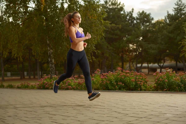 Kız sporcu sabah dışarıda, şehirde ağaçlarla çevrili bir parkta koşuyor. Aktif sağlıklı yaşam tarzı. Spor ve eğlence konsepti. — Stok fotoğraf