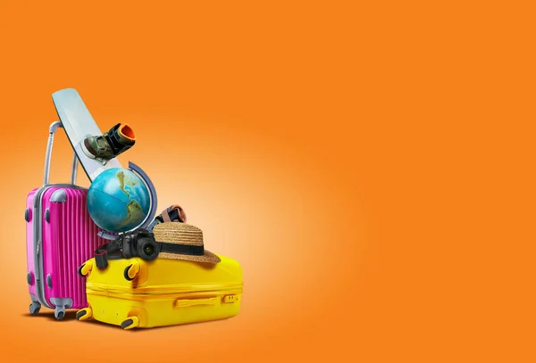 Purple and yellow suitcases against an orange background. There are a globe, wakeboard, hat and camera laying on them. Collage. Copy space, close-up. — Stock Photo, Image