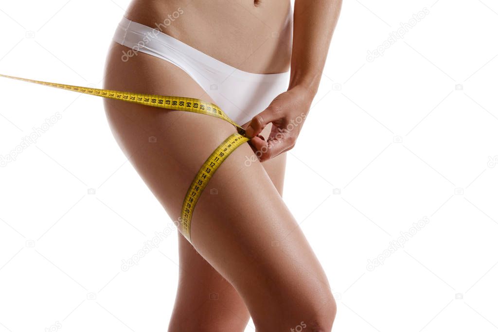 Perfect body of girl in white underwear measuring herself, posing isolated on white. Plastic surgery and aesthetic cosmetology concept. Close-up.