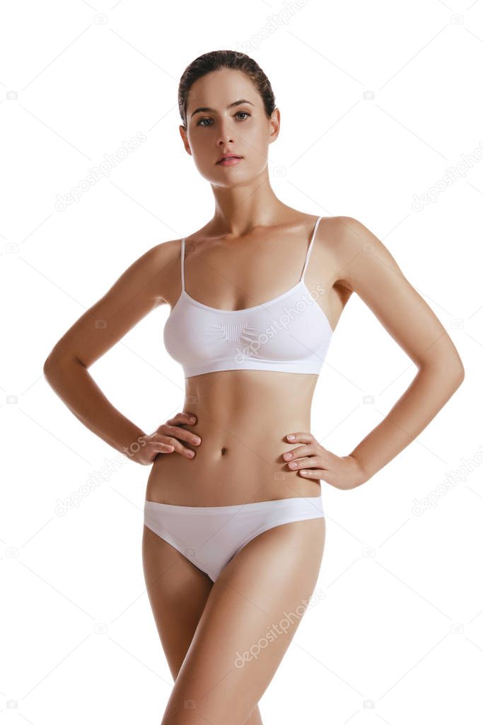 Young woman in white underwear, with bundled hair, hands on hips, posing isolated on white. Plastic surgery, aesthetic cosmetology. Close-up shot.