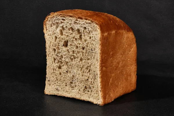 Pół bochenka świeżego, pysznego pieczonego szarego chleba na czarnym tle z przestrzenią do kopiowania. Zbliżenie, widok z boku — Zdjęcie stockowe