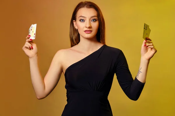 Blonďatá žena s jasným make-upem, v černých šatech ukazuje čtyři esa, pózuje na barevném pozadí. Hazard, poker, kasino. Detailní záběr. — Stock fotografie