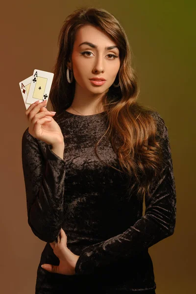 2つの顔を示す黒ベルベットのドレスやジュエリーでブルネットの女性は、カラフルなスタジオの背景に対してポーズ。ギャンブル、ポーカー、カジノ。閉鎖. — ストック写真