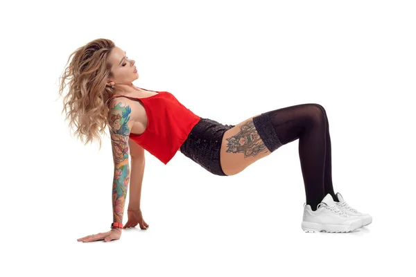 Sexy blond twerk woman with tattoed body and long curly hair is posing in studio. — Stock Photo, Image