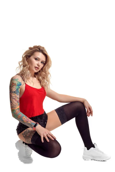 Szexi szőke twerk nő tattoed test és hosszú göndör haj pózol a stúdióban. — Stock Fotó
