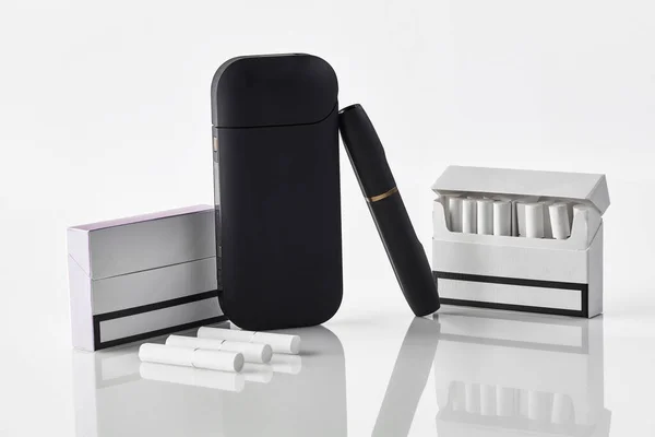 Černá elektronická cigareta, baterie, dva balíčky a jeden z nich je otevřený, tři tepelné tyčinky izolované na bílém. Systém vytápění tabáku. Zavřít — Stock fotografie