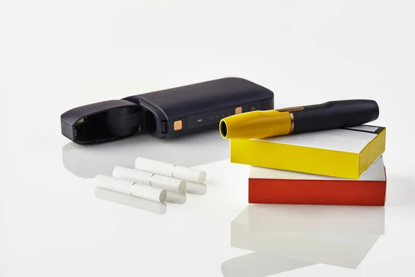 Fekete elektronikus cigaretta van a csomagolás piros és sárga oldalán, nyitott akkumulátor, három fűtő pálca elszigetelt fehér. Fűtés dohányrendszer. Közelről. — Stock Fotó