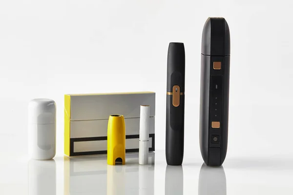 Egy csomag, új generációs fekete elektronikus cigaretta, sárga kupak, akkumulátor, tisztább, egy fűtőpálca elszigetelt fehér. Fűtés dohányrendszer. Közelről. — Stock Fotó