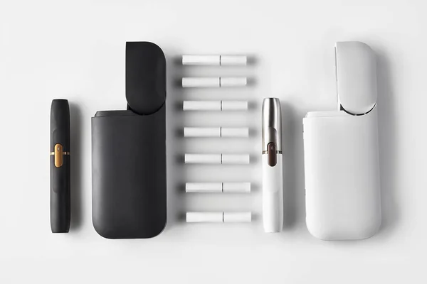 Új generációs fekete-fehér, két elektromos cigaretta és két nyitott akkumulátor, hét hőnyaláb, fehér alapon elszigetelve. Fűtés dohányrendszer. Közelről. — Stock Fotó