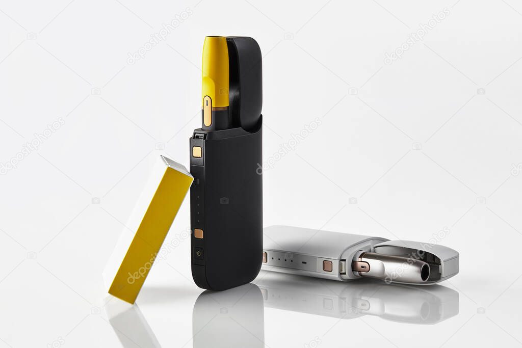 New generation, two black and yellow electronic cigarettes in open batteries and matchbox isolated on white. Heating tobacco system. Close up
