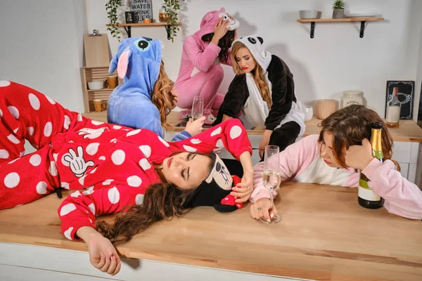 Chicas vestidas con pijamas de felpa en forma de personajes de dibujos animados disfrutando de despedida de soltera. Algunos se emborracharon, se durmieron en encimeras de cocina. Primer plano —  Fotos de Stock