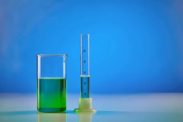 Líquido Verde Vaso Precipitados Cilindro Medición Fondo Azul Investigación Laboratorio — Foto de Stock