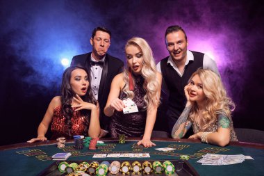 Bir grup yakışıklı genç kumarhanede poker oynuyorlar. Gençler büyük bir galibiyet için bahis oynuyorlar. Siyah duman arka planında kırmızı ve mavi arka farlara karşı masada poz veren kartlarına bakıyorlar. Çipler, para, kumar, e