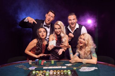 Bir grup komik sınıf arkadaşı kumarhanede poker oynuyor. Gençler büyük bir galibiyet için bahis oynuyorlar. Gülümsüyorlar ve masada siyah dumanlı kırmızı ve mavi arka farlara karşı poz veren iki as gösteriyorlar. Kartlar, çipler, para, ga