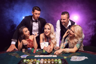Genç ve zengin bir grup kumarhanede poker oynuyor. Gençler büyük bir galibiyet için bahis oynuyorlar. Gülümsüyorlar ve masada siyah dumanlı kırmızı ve mavi arka farlara karşı poz veren iki as gösteriyorlar. Kartlar, çipler, para, kumar