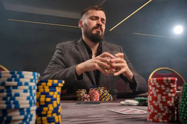 Klasik gri takım elbiseli atletik sakallı adam kumarhanede poker oynuyor. Üzerinde fişler ve kartlarla masada oturuyor. O, elinde bir bardak viski tutuyor ve kameraya bakıyor. Kumar bağımlılığı. Samimi duygular ve girişim