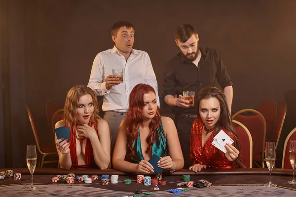 熱心な同僚はカジノでポーカーをしています 彼らは暗い煙の背景に対してテーブルで彼らの勝利 笑顔とポーズを祝っています カード チップ アルコール ギャンブル エンターテイメントの概念 — ストック写真