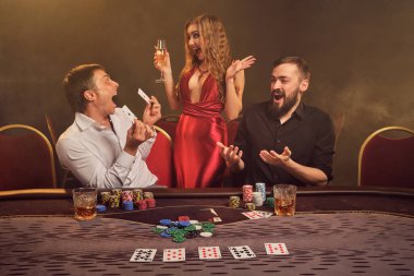 İki yakışıklı arkadaş ve muhteşem kadın kumarhanede poker oynuyorlar. Kazandıkları için mutlular, seviniyorlar ve arka planda sarı bir fonda poz verirken iyi vakit geçiriyorlar. Kartlar, fişler, para, kumar, eğlence