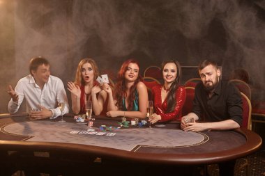 Zengin ortaklar kumarhanede poker oynuyor. Zaferlerini kutluyorlar, gülümsüyorlar ve çok heyecanlı görünüyorlar. Bir sahne ışığı altında, karanlık bir duman arka planına karşı poz veriyorlar. Kartlar, fişler, para, alkol, kumar, eğlence dolandırıcılığı