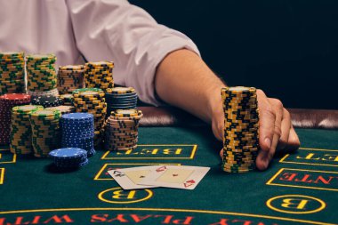 Beyaz gömlekli şık bir adamın yakın plan fotoğrafı kumarhanedeki masada duman içinde poker oynuyor. Elinde bazı çipler tutuyor. Kumar bağımlılığı. Samimi duygular ve eğlence konsepti.