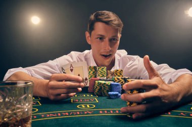 Beyaz gömlekli zeki bir adamın yakın plan çekimi, kumarhanedeki masada beyaz bir spot ışığına karşı duman içinde poker oynamaktır. Zaferine sevinerek elinde iki as ve biraz fiş tutuyor. Kumar bağımlılığı. Samimi duygular ve 