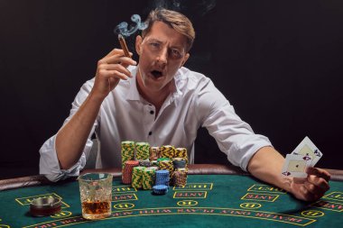 Beyaz gömlekli görkemli adam kumarhanenin masasında duman içinde poker oynuyor. Zaferine seviniyor ve elinde iki as ile puro içiyor. Kumar bağımlılığı. Samimi duygular ve eğlence konsepti.