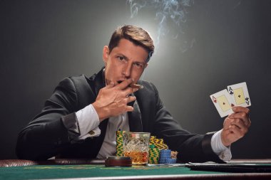 Siyah takım elbiseli ve beyaz gömlekli yakışıklı kumarhanenin masasında beyaz bir spot ışığına karşı duman içinde poker oynuyor. Elindeki iki ası göstererek, puro içerek ve kameraya bakarak kazandığı zafere seviniyor. Kumar reklamı