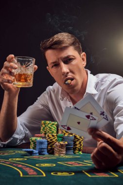 Beyaz gömlekli görkemli kişi kumarhanenin masasında beyaz bir spot ışığına karşı duman içinde poker oynuyor. Zaferini puro içerek ve viski içerek kutluyor. Elinde iki as var. Kumar bağımlılığı. Samimi duygular ve