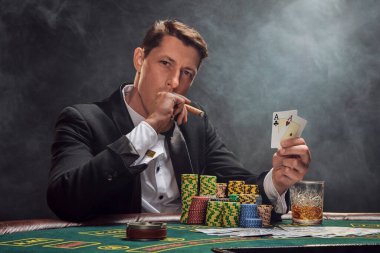 Siyah takım elbiseli ve beyaz gömlekli zeki bir adam kumarhanede beyaz bir spot ışığına karşı duman içinde poker oynuyor. Elindeki iki ası göstererek, puro içerek ve kameraya bakarak zaferine seviniyor. Kumar bağımlılığı