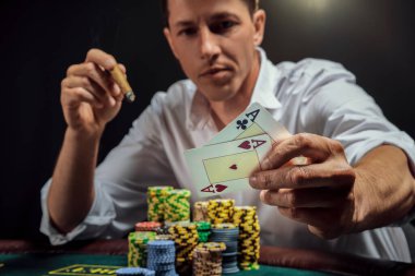 Beyaz gömlekli atletik adam kumarhanenin masasında beyaz bir spot ışığına karşı duman içinde poker oynuyor. Zaferine seviniyor ve elinde iki as ile puro içiyor. Kumar bağımlılığı. Samimi duygular ve eğlence