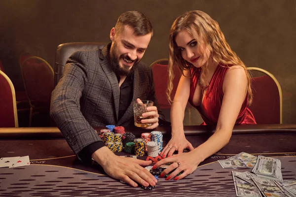 Charming wealthy couple are playing poker at a casino.