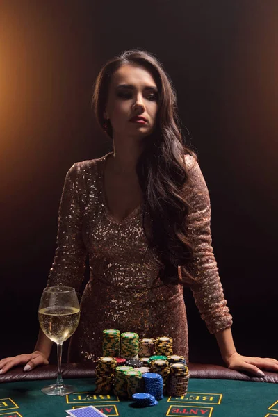 完璧な髪型と明るい化粧を持つブルネットの女の子はギャンブルテーブルに対してポーズをとっています。カジノ,ポーカー. — ストック写真
