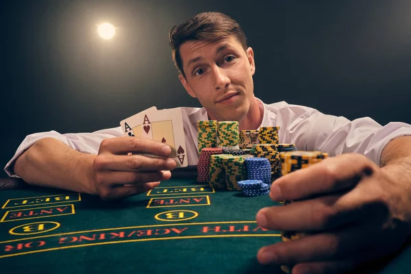 Beyaz gömlekli zeki bir erkeğin yakın plan çekimi, kumarhanedeki masada beyaz bir spot ışığına karşı duman içinde poker oynamaktır. Zaferine sevinçle seviniyor. Elinde iki as ve birkaç fiş var. Kumar bağımlılığı. Samimi duygular ve girişim