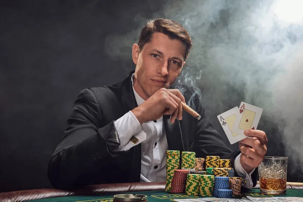 Siyah takım elbiseli ve beyaz gömlekli şık bir adam kumarhanedeki masada beyaz bir spot ışığına karşı duman içinde poker oynuyor. Elindeki iki ası göstererek, puro içerek ve kameraya bakarak kazandığı zafere seviniyor. Kumar bağımlısı.