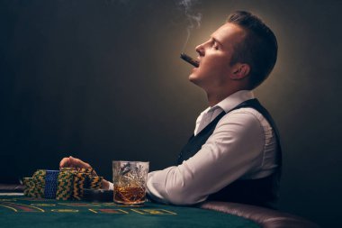 Beyaz gömlekli ve siyah yelekli yakışıklı bir erkek masada yan yana oturmuş puro içiyor. Kumarhanede siyah arka planda bir ışık hüzmesiyle poker oynuyor. Kartlar ve çiplerle riskli kumar eğlencesi