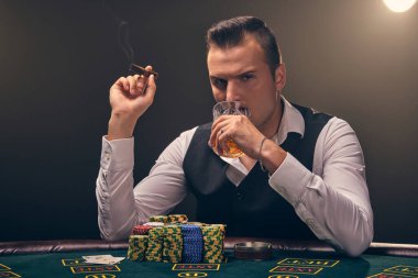 Beyaz gömlekli ve siyah yelekli zengin yetişkin bir adam elinde bir puro tutuyor ve viski içiyor. Kumarhanede siyah arka planda bir ışık hüzmesiyle poker oynuyor. Kart ve chi ile riskli kumar eğlencesi